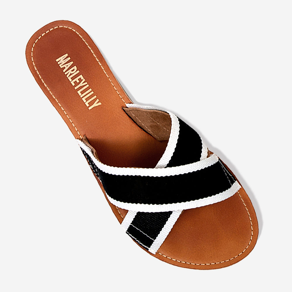 girl holding monogrammed criss cross sandals at the beach