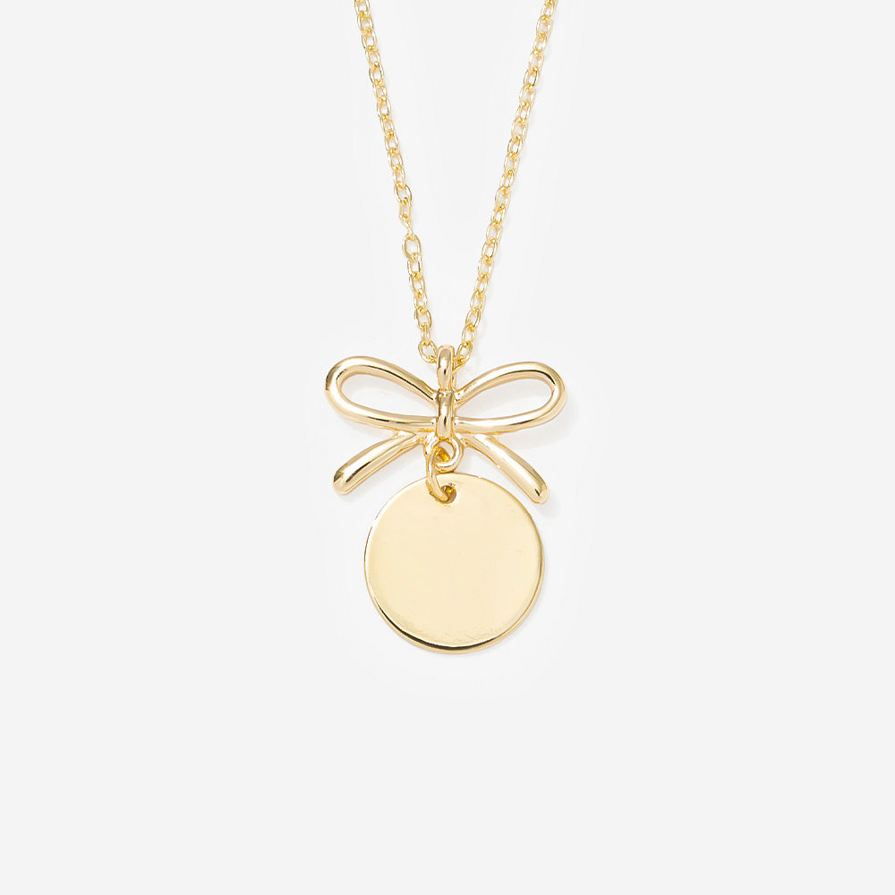 Silver bow necklace on marble with ribbon