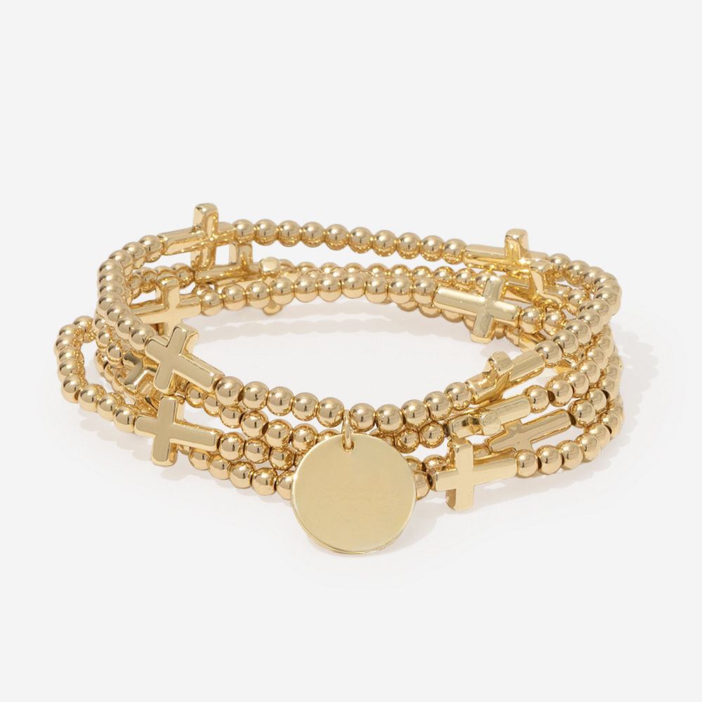 gold monogrammed cross bracelet stack scattered