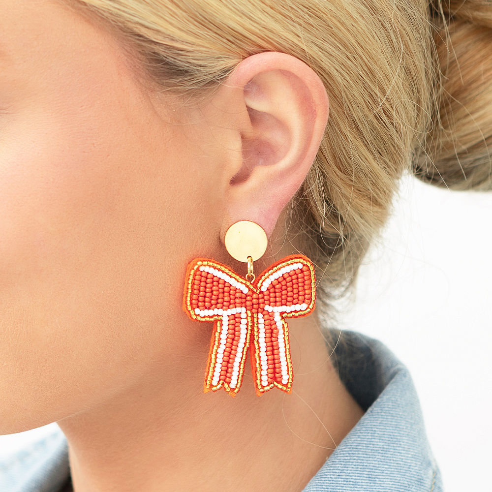 orange gameday bow earrings on green background