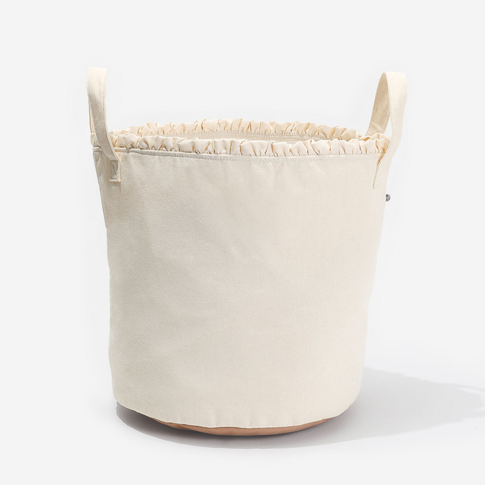 tan and ivory storage basket with blankets and magazines