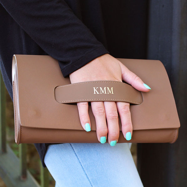 monogrammed brown clutch paired with a black shirt and jeans