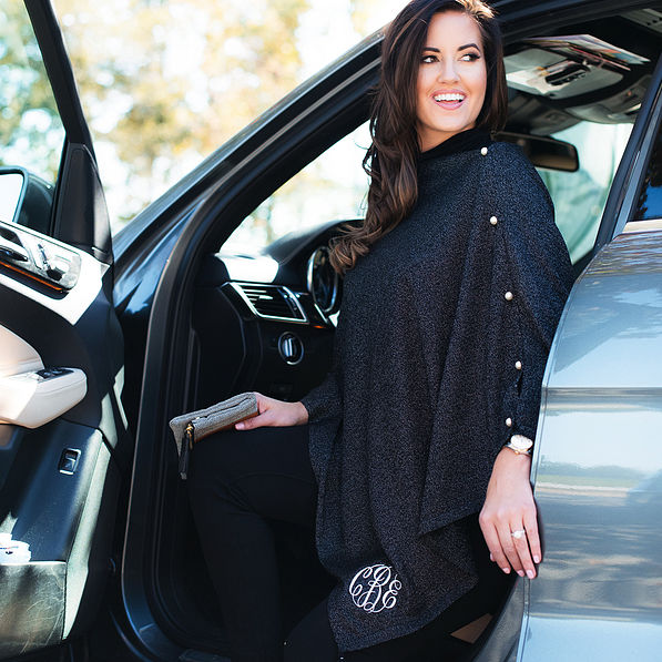 girl getting our of a car wearing the Monogrammed Luxe Poncho in black shimmer