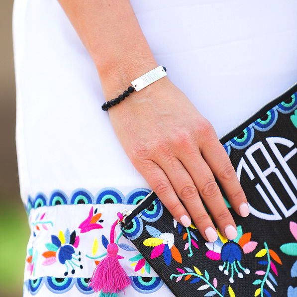 monogrammed black beaded bracelet in black holding clutch