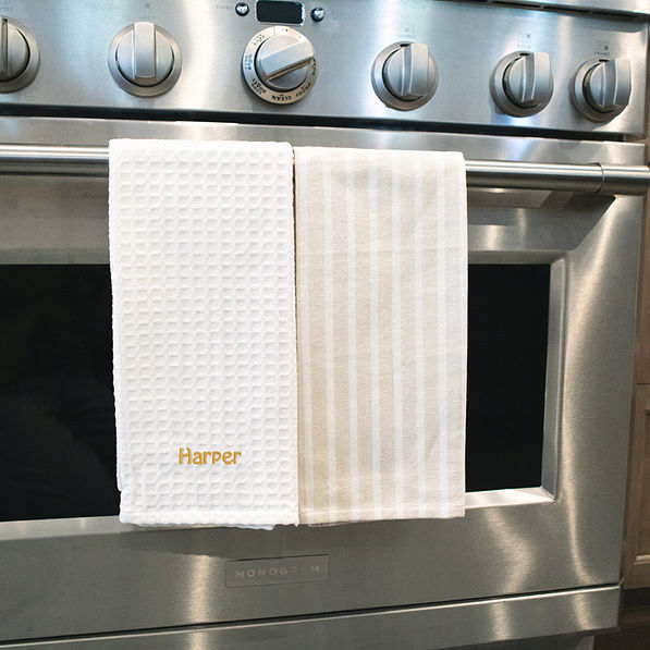 dish towel set in khaki with embroidered name hanging on stove
