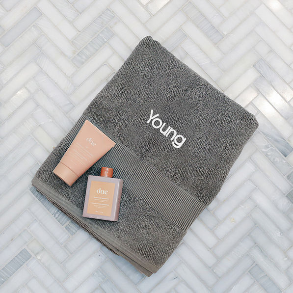 monogrammed bath towel in grey laying on tile floor with name new