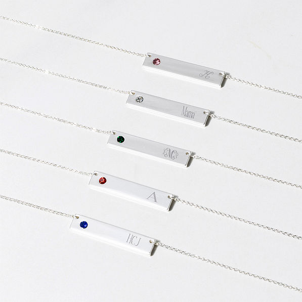five birthstone bar necklaces laid out with various engravings