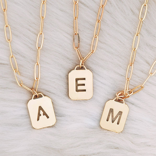 Initial Tag necklace A, E, M on carpet rug