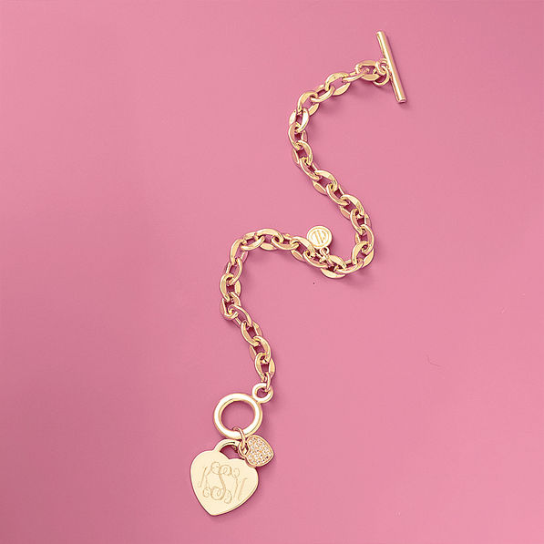 monogrammed heart bracelet in gold flatlay on pink