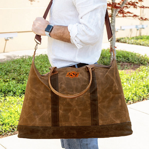 Oklahoma State SP23 Waxed Canvas Weekender on man's shoulder
