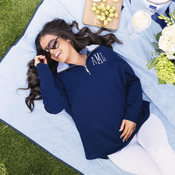 girl wearing monogrammed quarter zip sweatshirt in navy blue shells on picnic blanket