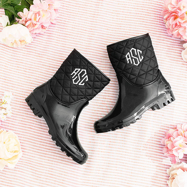 black rain boots on pink striped background