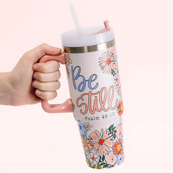 festive travel tumbler being held with pink background