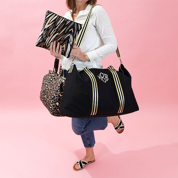 black and gold travel bag set with pink background