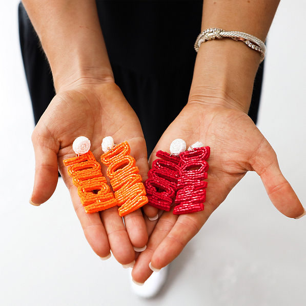 red and orange touchdown earrings in hand