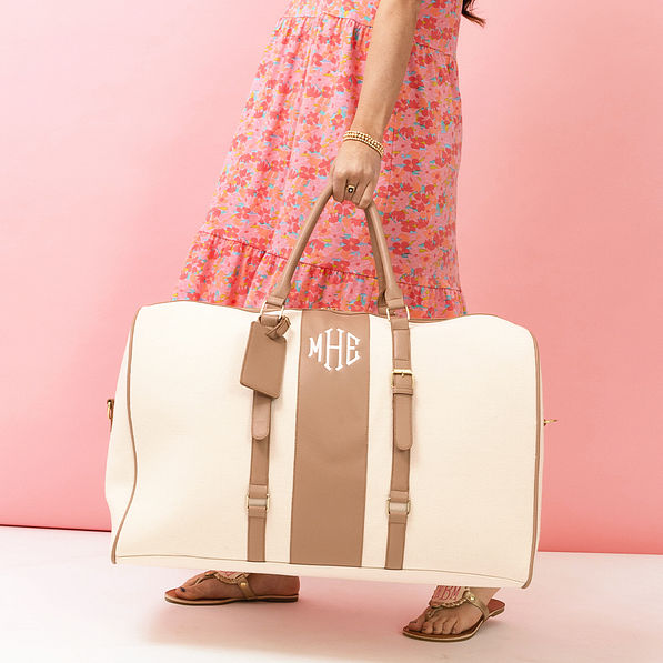 ivory weekender bag in hand with dress - up close