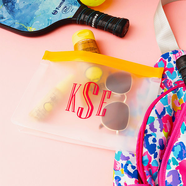 monogrammed orange sunscreen bag with sunscreen on pink paper