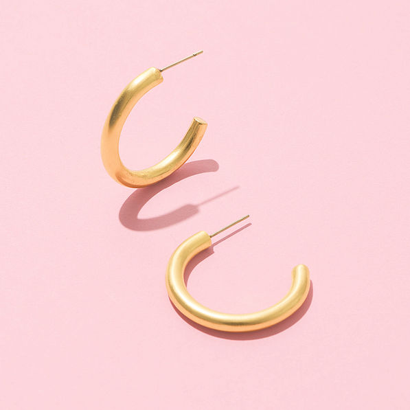 brushed hoop gold earrings on pink background