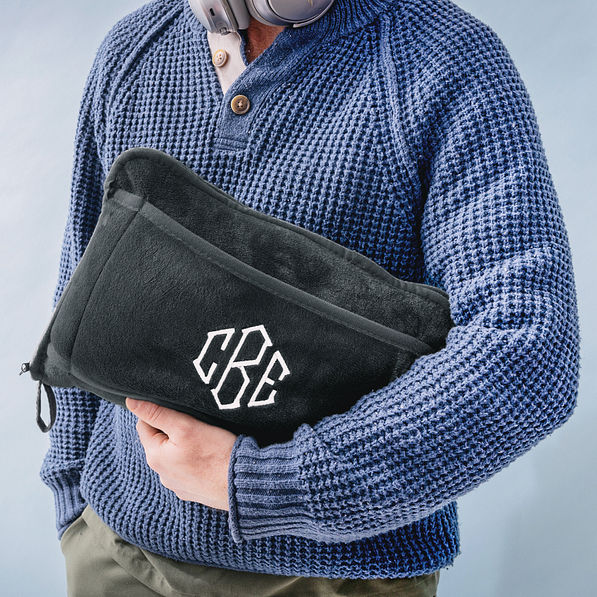 man holding monogrammed charcoal travel blanket pillow