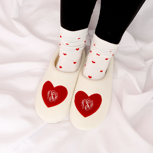 heart socks with monogrammed slippers on white sheet