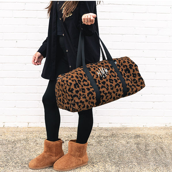 monogrammed sherpa fuzzy duffel bag in hickory leopard on wrist