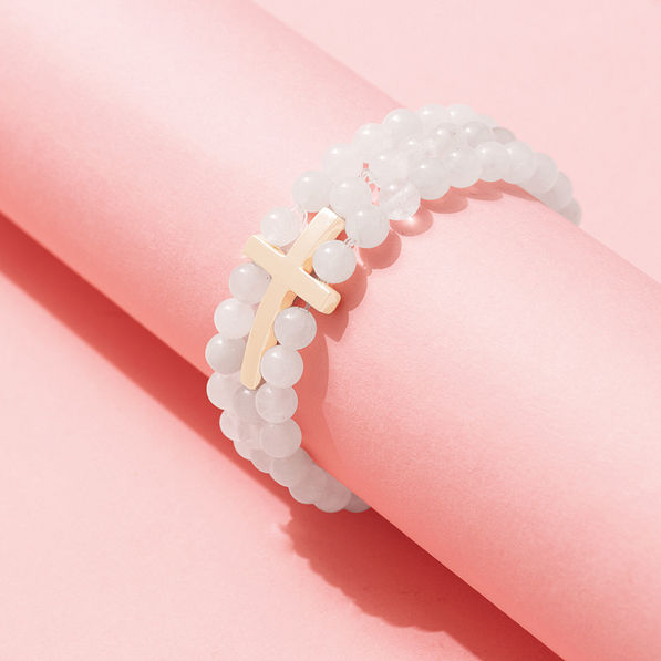 stretchy cross bracelet on pink paper