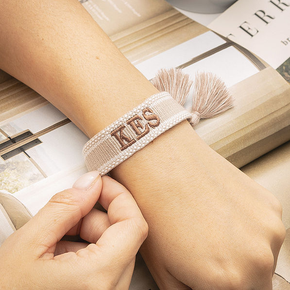 khaki monogrammed woven bracelet on wrist