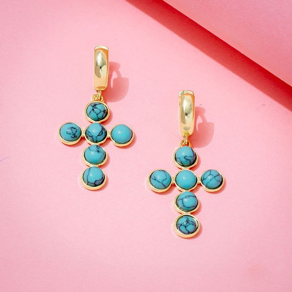 turquoise cross earrings on pink paper