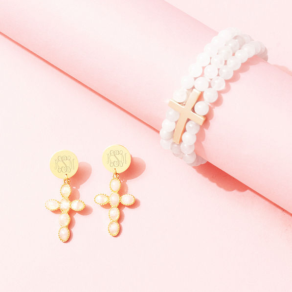 monogrammed cross earrings and stretchy cross bracelet on pink paper
