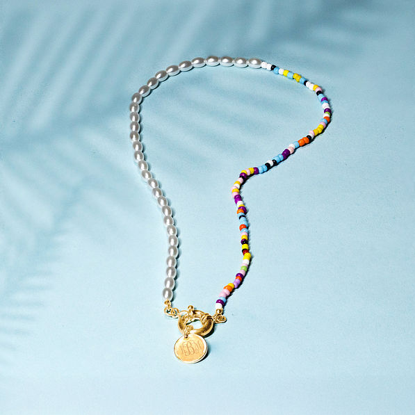 pearl seed bead necklace on blue paper with shadows