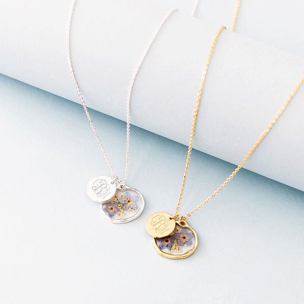 silver and gold forget me not necklaces on blue paper roll