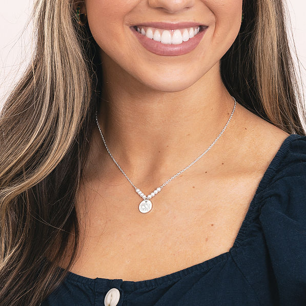 girl wearing silver monogrammed pearl necklace