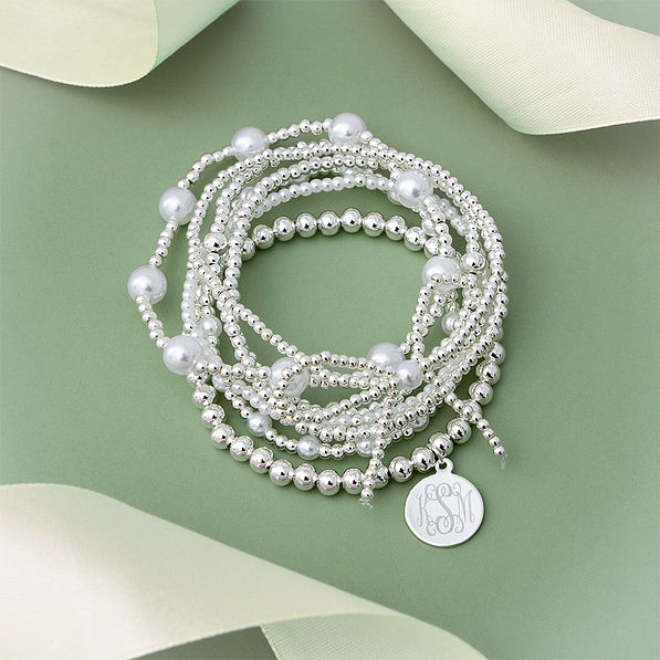 silver pearl bow bracelet stack on green background
