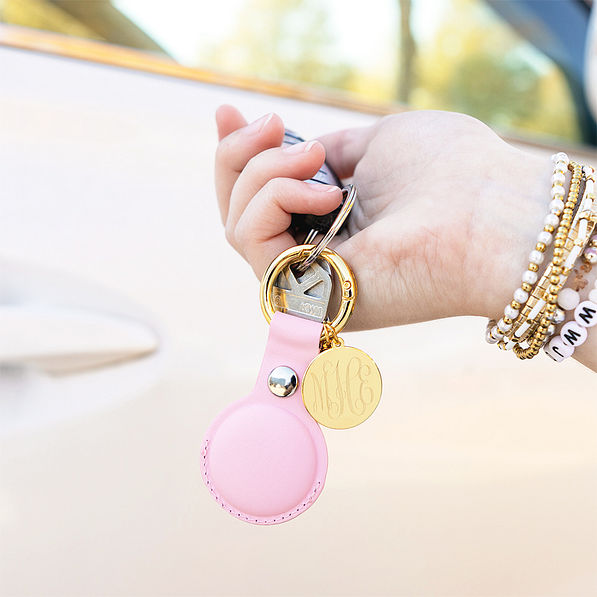 pink with gold airtag key chain in hand
