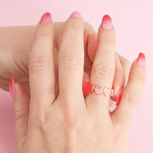 girl putting on pink gold heart ring