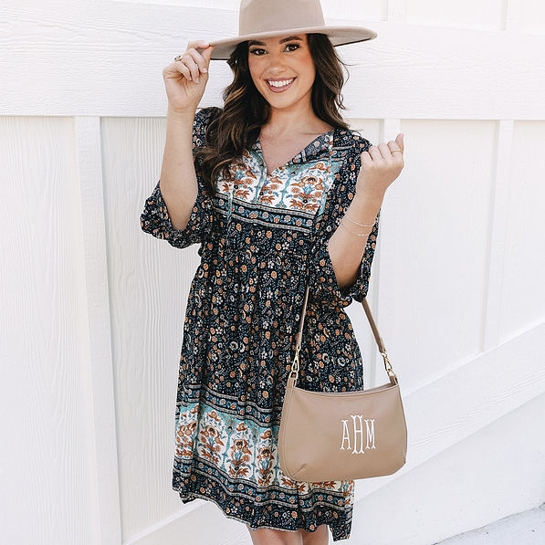 girl with monogrammed shoulder bag in taupe over arm