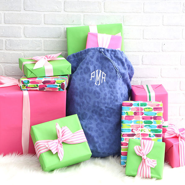 monogrammed gift sack with presents in front of brick wall