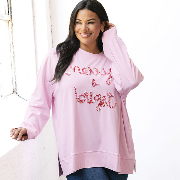 girl wearing merry and bright sweatshirt in light pink