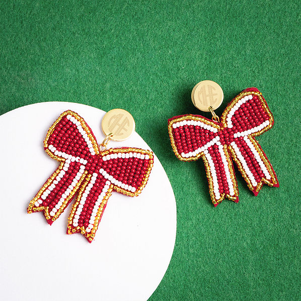 crimson gameday bow earrings on green background