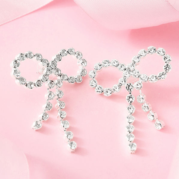 silver rhinestone bow earrings on pink background