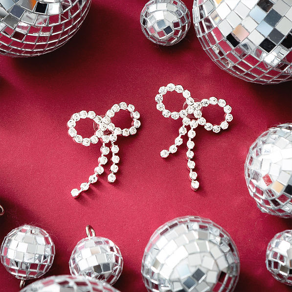silver rhinestone bow earrings on red background