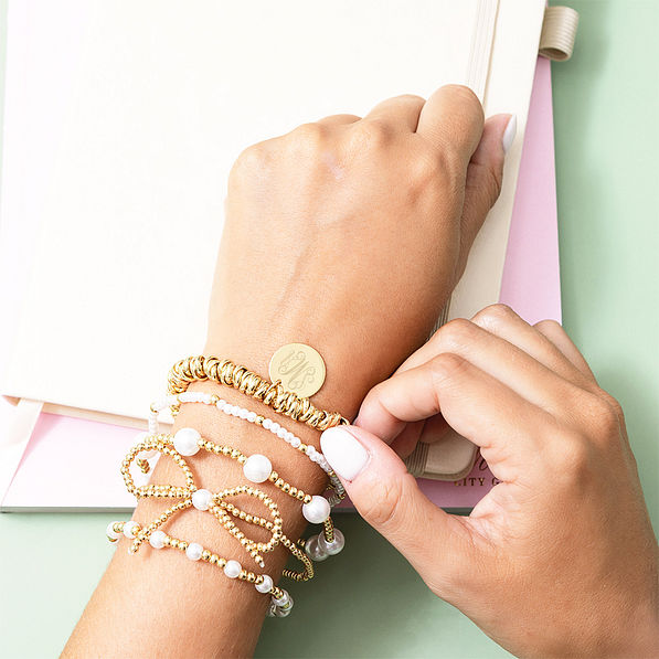 gold twisted knot bracelet on arm with bow bracelet