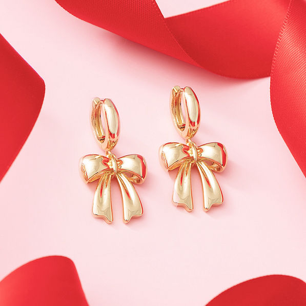 close up of bow huggie hoop earrings