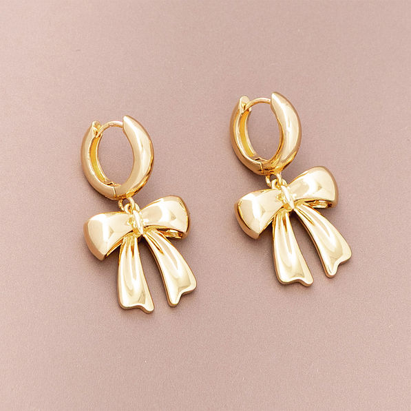 bow huggie hoop earrings on brown background