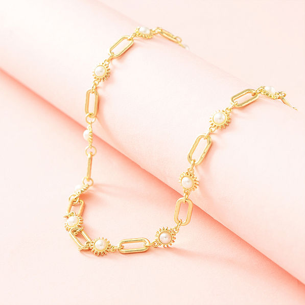gold pearl starburst necklace on pink background
