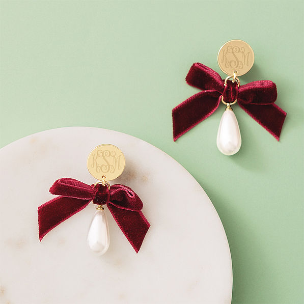 Monogrammed velvet bow earrings on green background