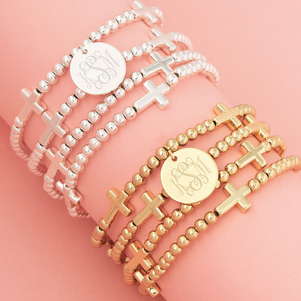 close up of monogrammed silver and gold cross bracelet stacks
