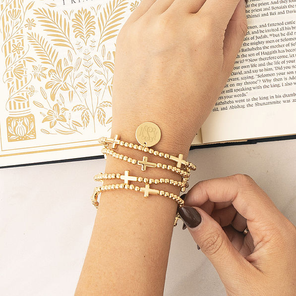 girl wearing gold monogrammed cross bracelet stack
