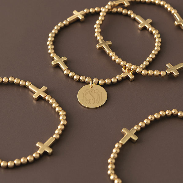 gold monogrammed cross bracelet stack scattered