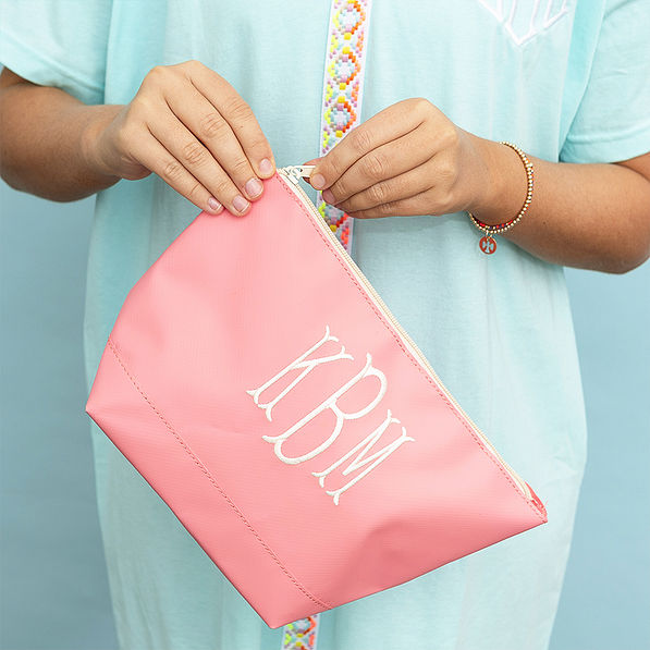 Coral monogrammed waterproof cosmetic pouch in hands